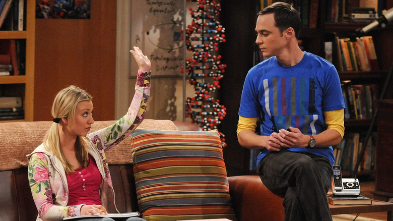 Penny raising her hand while Sheldon looks